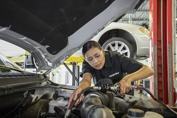 A Meineke mechanic completing oil change services